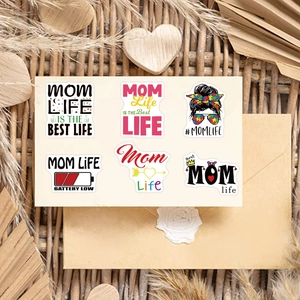 Close-up of waterproof Mom Life stickers with heart and messy bun motifs on light background