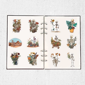 Artistic skull stickers with floral motifs arranged in a white ring-bound notebook