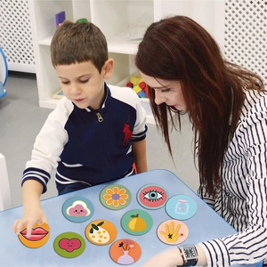 Child and teacher interacting with colorful cartoon sunshine doodle stickers on a blue desk