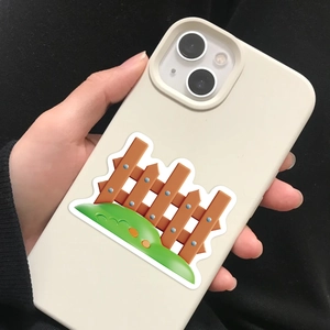 Close-up of a cream silicone iPhone case with cartoon fence and green grass graphics