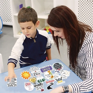 Child and adult decorating a desk with colorful Spanish Bible verse stickers for DIY