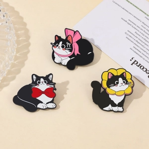 Detailed view of three cute enamel cat pins with pink bows and floral collars on a tray