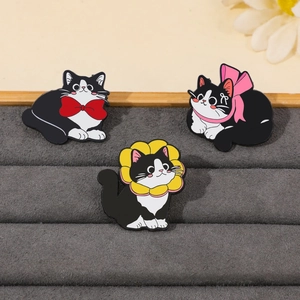 Detailed view of three enamel cat pins featuring red bowties and sunflower collars