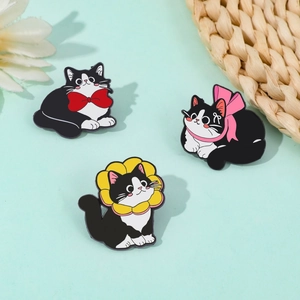 Close-up of three cute enamel cat pins with bowties on a mint green decorative background