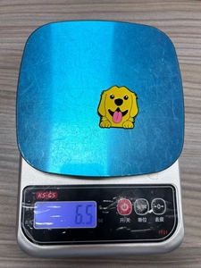 Detailweergave van een 6,5g schattige Golden Retriever emaille speld op een weegschaal