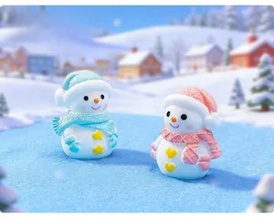 Close-up of pink and blue resin snowman figurines with scarves in a winter snow scene