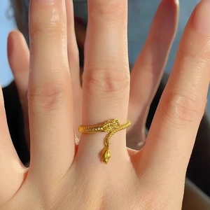 Golden dragon tail wrap ring with intricate scales and dangling charm on finger