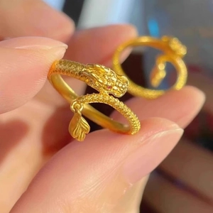 Macro shot of gold dragon ring featuring detailed scales, red eyes and a leaf charm
