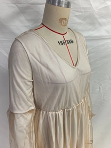 Détail d'une robe beige à col en V avec manches en tulle et taille haute plissée