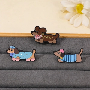 Vue détaillée de trois broches en émail de teckel mignonnes sur un plateau en velours