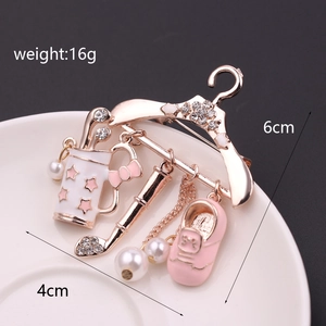 Detailed view of hanger-shaped brooch with golf bag, pearl, and pink sneaker charms