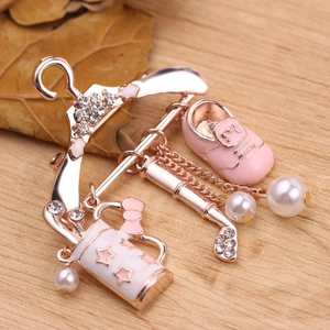 Detail of rose gold hanger brooch featuring pink enamel baby shoes and pearl charms