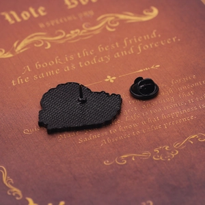 Détail d'un pin's médical en émail avec fermoir papillon posé sur un livre vintage