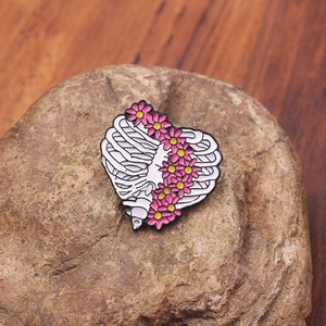 Détail d'une broche en émail montrant des côtes humaines et des fleurs roses