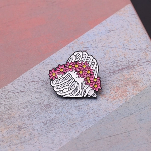 Détail de la broche en émail en forme de cage thoracique avec des marguerites roses et jaunes
