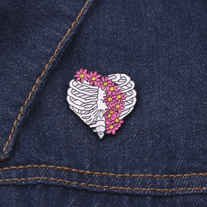 Détail de la broche en émail cœur cage thoracique avec fleurs roses sur du denim