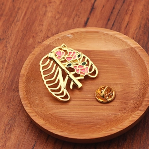 Détail macro de la broche poumon avec fleurs en émail rose sur alliage doré