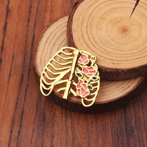 Gros plan sur la broche cage thoracique dorée avec fleurs en émail sur support bois