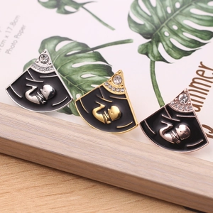 Detailweergave van medische foetusbroches in goud, zilver en roségoud met emaille finish