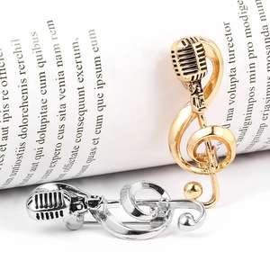 Close-up of gold and silver vintage microphone brooches with music note detailing