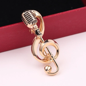 Detail of vintage microphone and treble clef gold brooch with polished finish