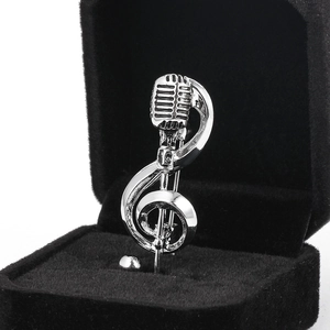 Detail of vintage microphone and treble clef music brooch in silver finish on jewelry box
