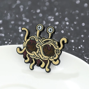 Close-up of Flying Spaghetti Monster enamel pin with yellow noodles and red meatballs