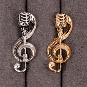 Retro microphone and musical note brooch in gold and silver finish on gray velvet