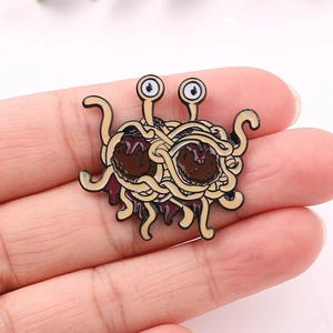 Detailed view of a Flying Spaghetti Monster enamel pin held by hand for size reference