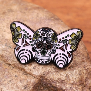 Detail of colorful enamel sugar skull butterfly brooch on a textured natural stone base