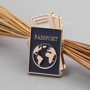 Macro detail of navy blue passport enamel pin with gold Earth emblem and travel tickets
