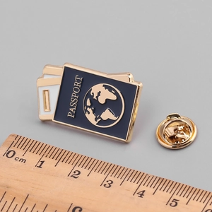 Gold-plated passport enamel pin with blue globe and butterfly clutch on gray background