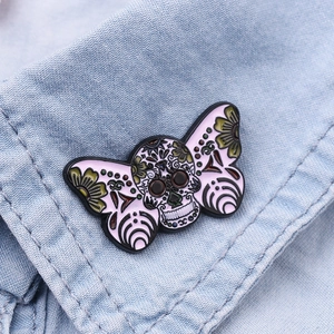 Detail of pink moth sugar skull enamel pin on light blue denim collar jacket