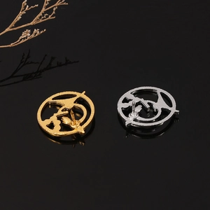 Detailed view of mockingjay bird brooches in gold and silver finish on reflective black
