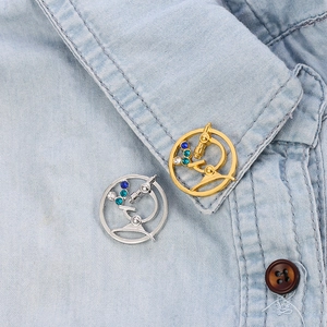 Detailed close-up of microscope brooch with rhinestones on blue denim shirt collar