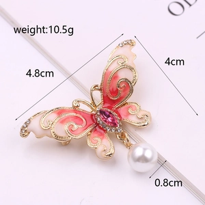 Macro detail of enamel butterfly brooch with crystal accents and white pearl pendant
