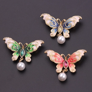 Three elegant butterfly brooches with enamel wings and pearls on black background