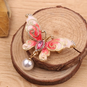Macro detail of enamel butterfly brooch with pink zircon and white pearl pendant