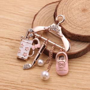 Detail of rose gold hanger brooch with enamel charms, pearls and crystals on wood