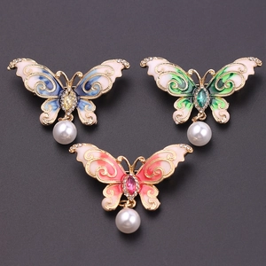 Three elegant butterfly brooches with enamel, rhinestones and pearl pendants on black