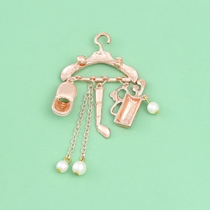 Rose gold golf hanger brooch with golf clubs, hat, and white pearls on mint background