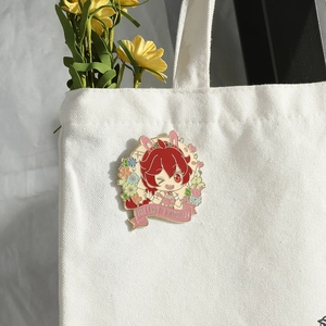 Anime enamel pin with rabbit girl and flowers attached to a white canvas bag