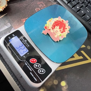 Detailed scale view showing the weight of this colorful anime enamel pin at 32.3 grams