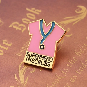 Detail of pink scrub enamel pin with stethoscope and Superhero in Scrubs text on book