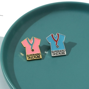 Macro shot of enamel pins featuring scrubs and the text Superhero in Scrubs