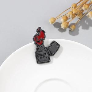 Détail du pin's en émail gris avec flamme rouge et texte gravé 'BURN IT ALL'