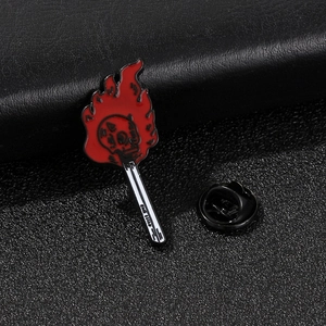 Vue macro d'un pin's émaillé en forme d'allumette enflammée avec crâne sur cuir noir