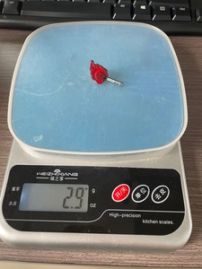 Détail d'un pin's en émail crâne enflammé sur une balance numérique pesant 2,9g