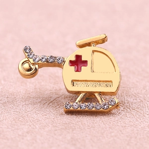 Golden helicopter brooch with white rhinestones and a red medical cross on pink leather