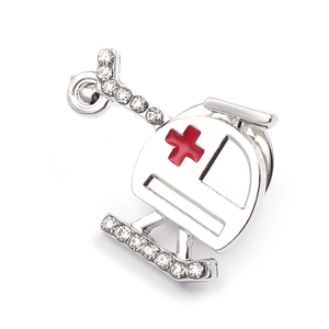 Detailed macro view of a silver helicopter brooch with red cross and sparkling rhinestones